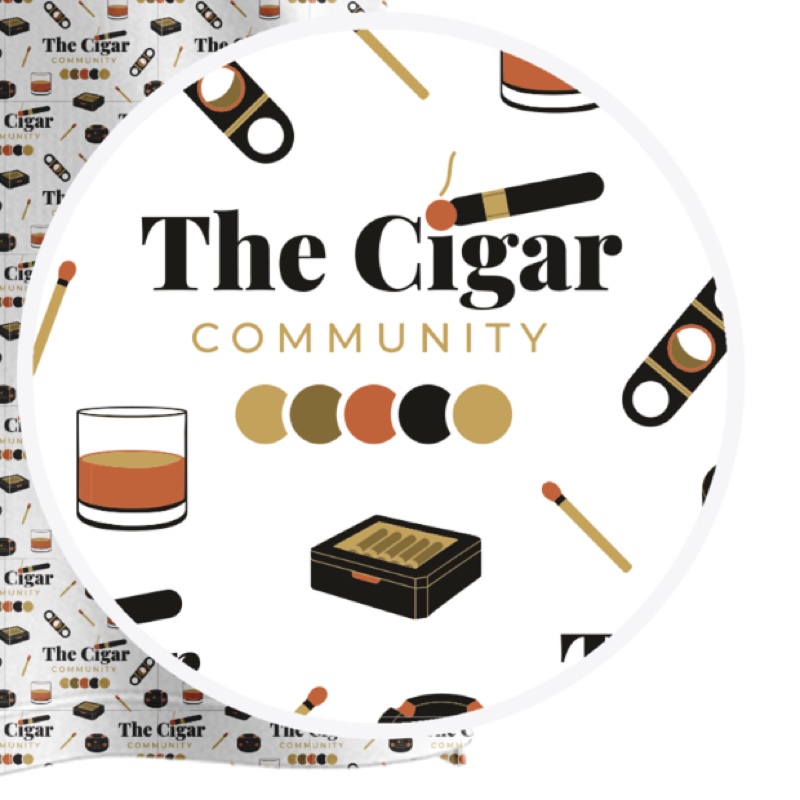 Close-up of the Ash White print — the Cigar Community lockup surrounded by a cutter, a lit cigar, a match and a humidor